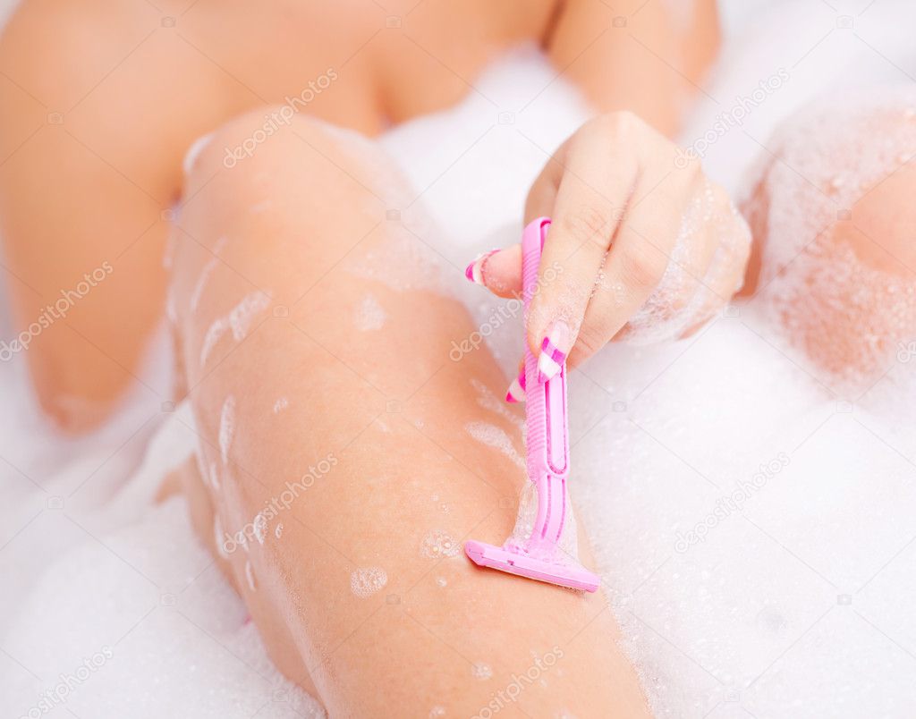 Closeup of a hand of a young caucasian woman shaving legs