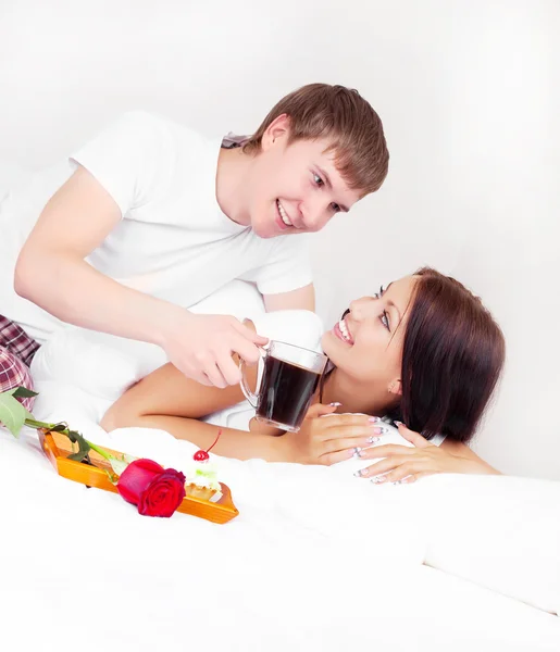 若い男がベッドの中で彼のガール フレンドをもたらすローズとコーヒー — ストック写真