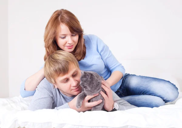 幸せな若いカップル 男にフォーカスが 猫と自宅のベッドの上 — ストック写真