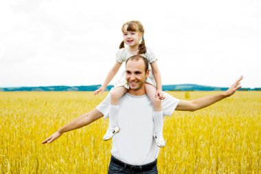 Happy young father and his daughter having fun at the wheat field (focus on the man) clipart