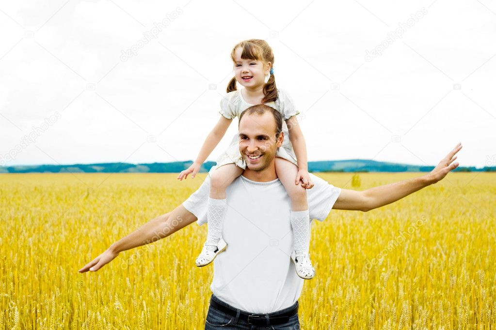 Happy young father and his daughter having fun at the wheat field (focus on the man)