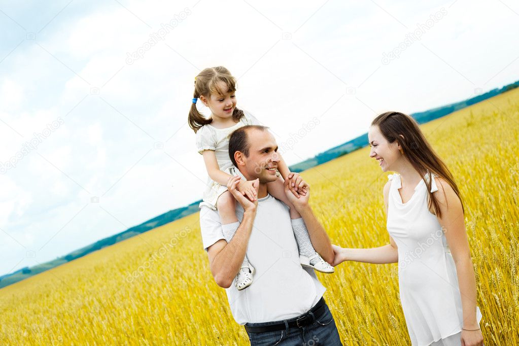 Happy family; young mother, father and their daughter having fun at the wheat field (focus on the man)