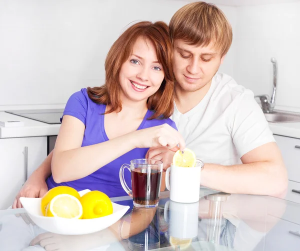 快乐的年轻夫妇 在家里的厨房里喝茶的柠檬 — 图库照片