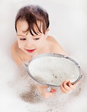 rahatlatıcı banyo köpüğü ile ve aynaya bakarak küçük kızla