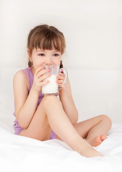 可爱的小女孩 在家里的床上喝牛奶 — 图库照片