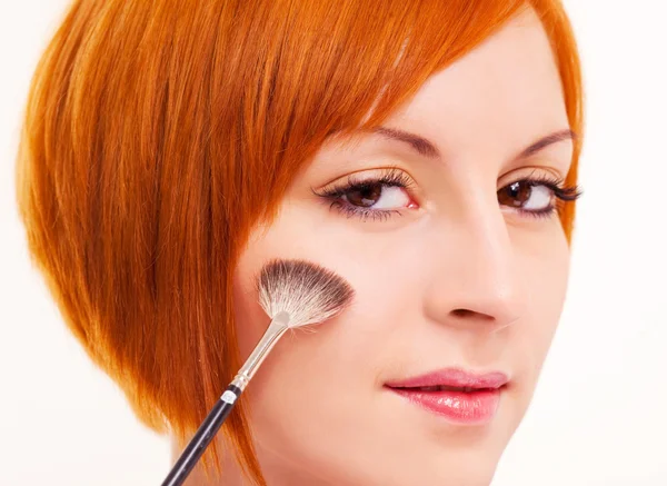 Beautiful young woman applying rouge on her face — Stock Photo, Image