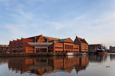 The historic building of the Baltic Philharmonic Orchestra with a ship in the background. Gdansk, Poland. clipart