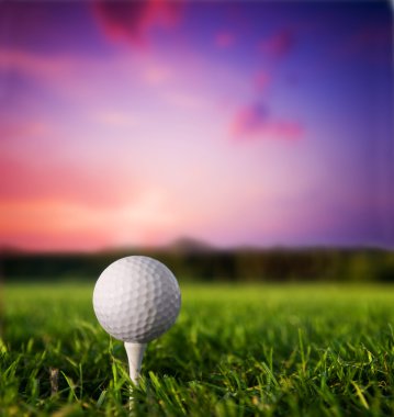Golf ball on tee at sunset clipart
