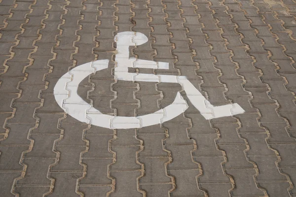 Símbolo para deficientes pintado em asfalto escuro . — Fotografia de Stock