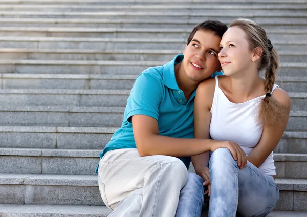 Young loving couple sitting on stairs and looking in the sky — Stock Photo, Image