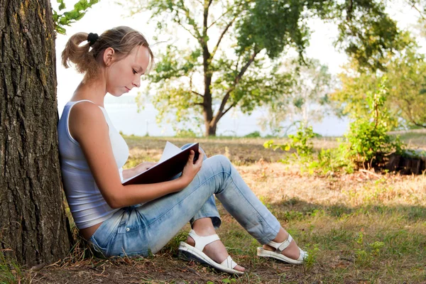 Junge Frau liest Buch im Park — Stockfoto