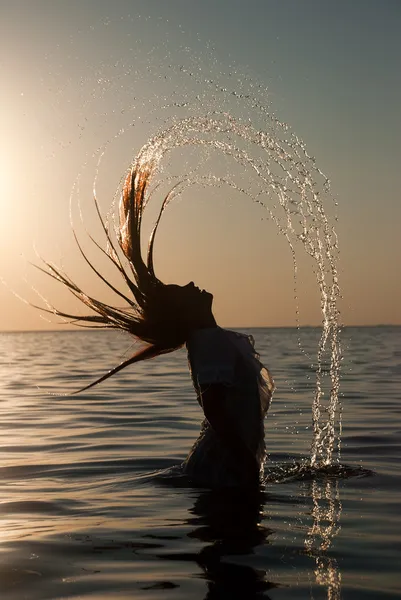 Motion freeze su una ragazza spruzzando l'acqua di mare con i capelli — Foto Stock