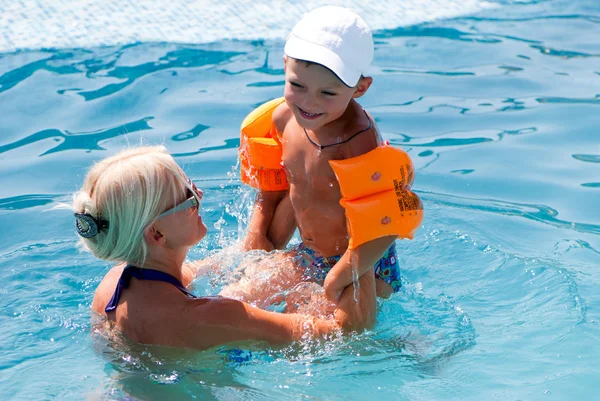 Красивая женщина и маленький мальчик купаются в бассейне — стоковое фото