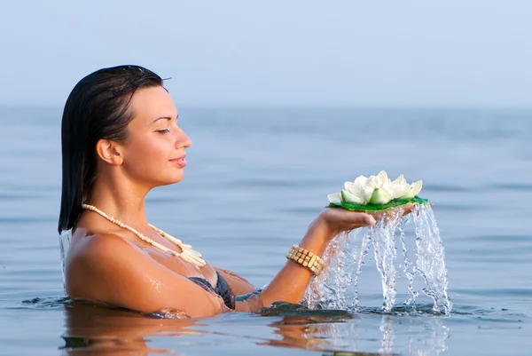 Het meisje met een bloem in handen tegen zee — Stockfoto