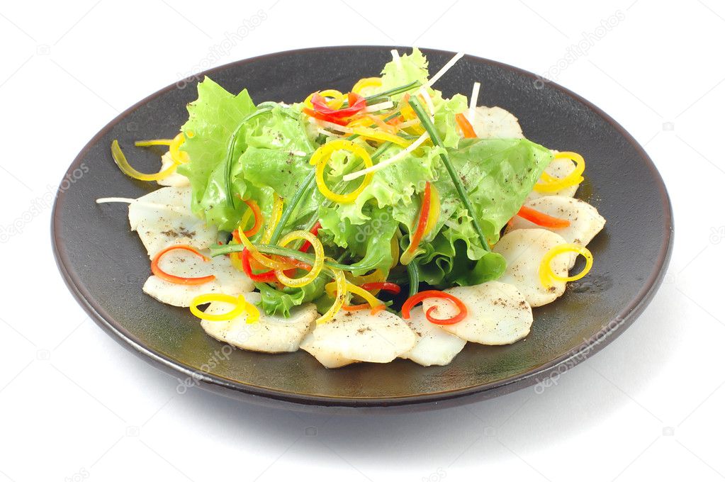 Salad with vegetables and fish close up on a white background