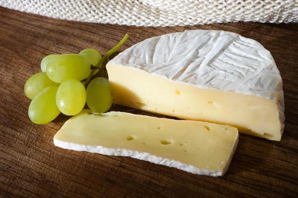 stock image Cheese and grapes on wooden board