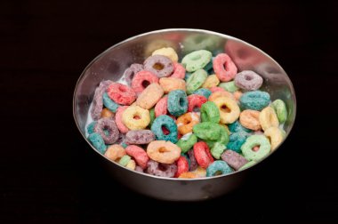 A bowl of looped cerals isolated on black background clipart