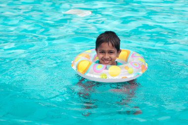 Handsome Indian kid playing in the pool clipart