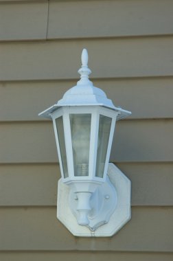 A white porch light against a brown vinal siding clipart