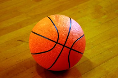 basketball in the spotlight resting on the hardwood floor clipart