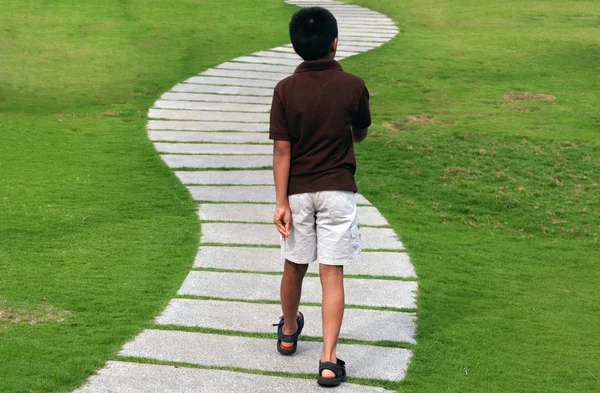 A toddler walking down the path in a park