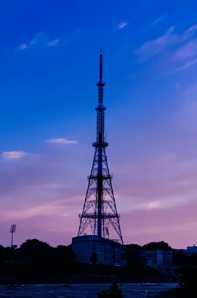 Una torre de telecomunicaciones alta durante una puesta de sol tropical — Foto de Stock