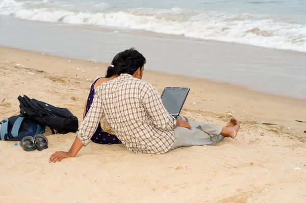 Пара с ноутбуком на пляже — стоковое фото