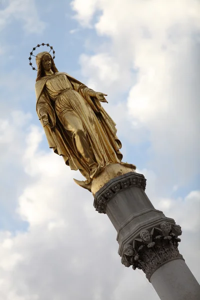 Estatua de la Virgen María hecha de oro contra un cielo azul — Foto de Stock