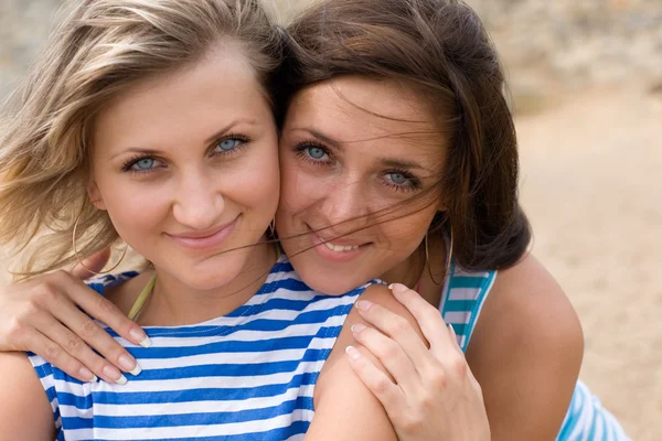 Zbliżenie dwóch młodych kobiet, uśmiechając się na plaży — Zdjęcie stockowe
