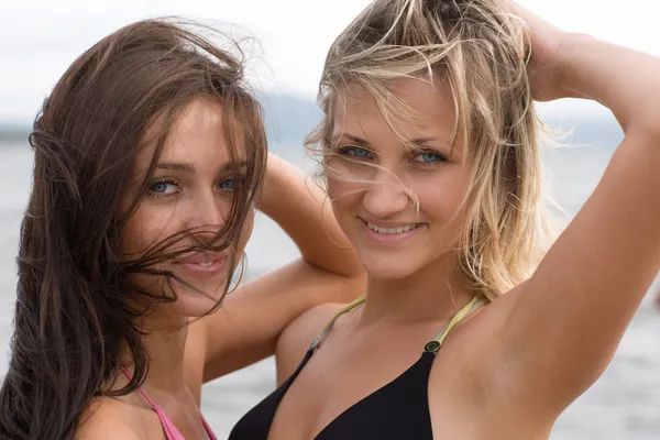 Крупный план двух молодых женщин, улыбающихся на пляже — стоковое фото