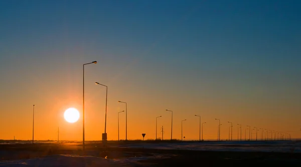 Viajando rápido por uma estrada aberta em linha reta até o pôr do sol . Fotos De Bancos De Imagens