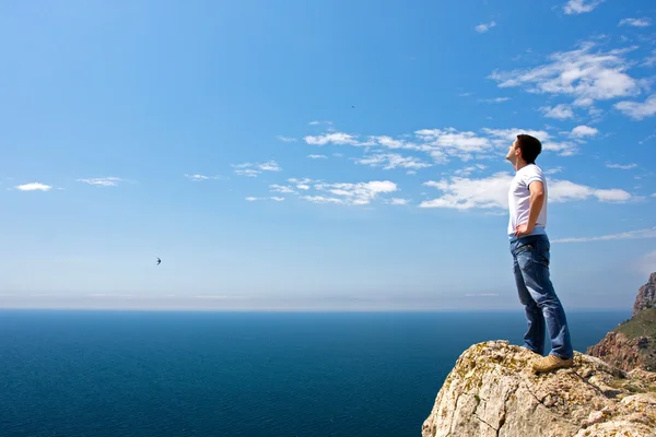 年轻男子站在岩石上 在海上寻找 — 图库照片