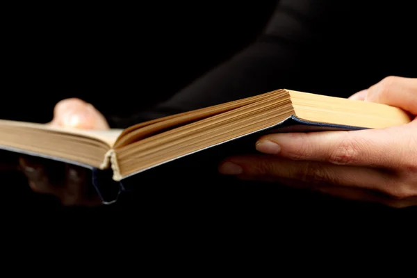 stock image Open book in hands on black background