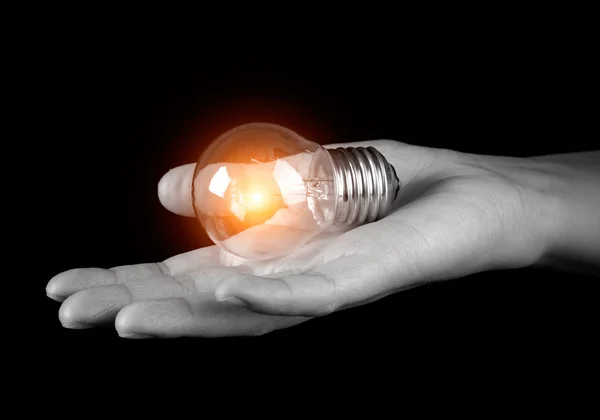 Hand holding light bulb isolated on black — Zdjęcie stockowe