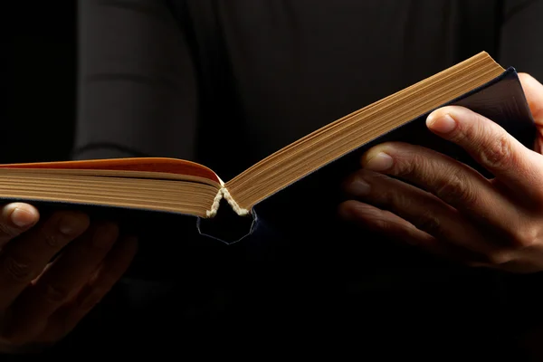 Открытая книга в руках на черном фоне — стоковое фото