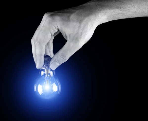Mão segurando lâmpada isolada em preto — Fotografia de Stock