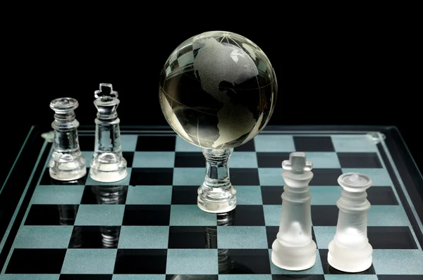 水晶棋子上具有全球忐忑不安的行黑色背景 — 图库照片
