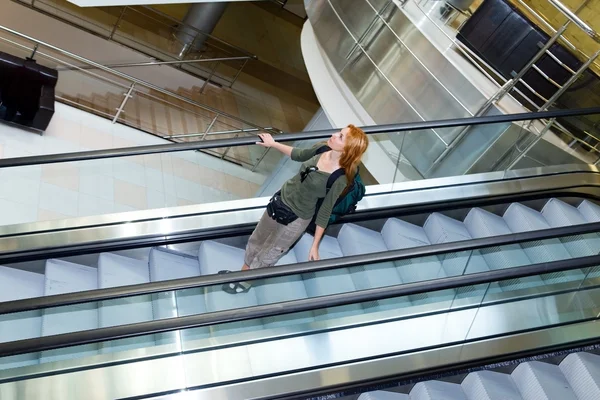 Young woman with backpack on the escalator — Stock Photo, Image