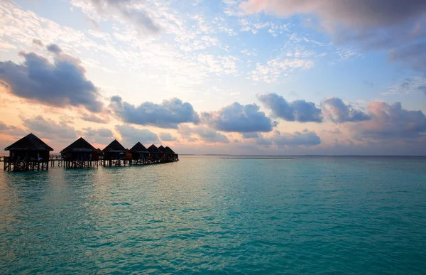 Isola nell'oceano, Maldive. Villa su pile sull'acqua al tramonto del tempo . — Foto Stock