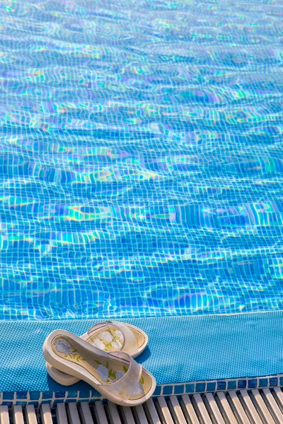 Tofflor ligger på gränsen till pool — Stockfoto