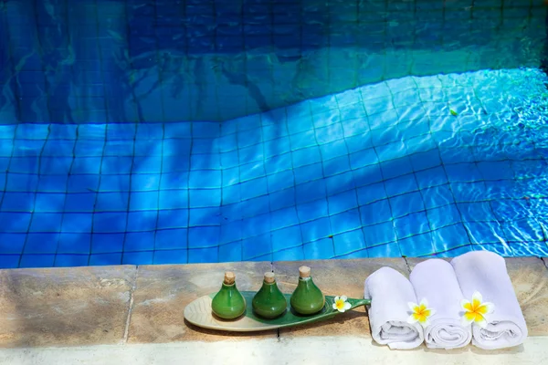 Handdoeken en middelen voor spa van het verlaten op de rand van het zwembad — Stockfoto