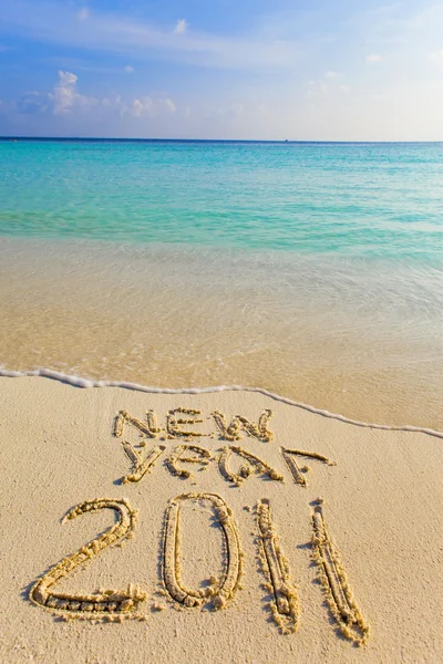 On sand at ocean edge it is written "2011" — Stock Photo, Image