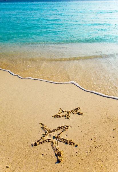 Drawing on sand on a theme of rest - a starfish and a small fish — Stock Photo, Image