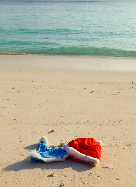 Twee nieuwjaarskappen van de kerstman op het strand — Stockfoto