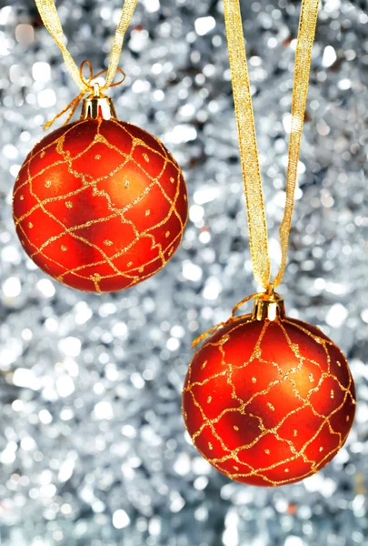 Two red New Year's balls hang on gold ribbons on a silvery background — Stock Photo, Image