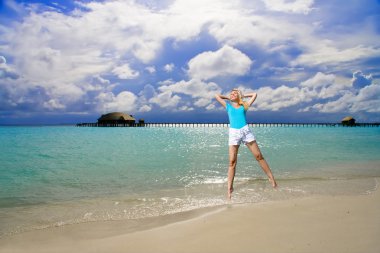 Kız okyanus kıyısında atlıyor, Maldivler 'de.