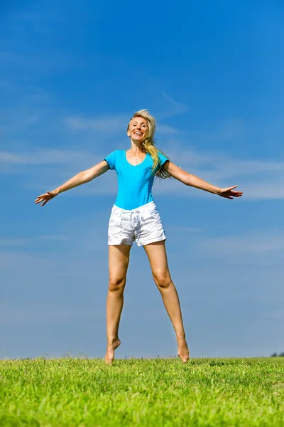 Η ευτυχισμένη νεαρή γυναίκα πηδάει στο χωράφι. — Φωτογραφία Αρχείου