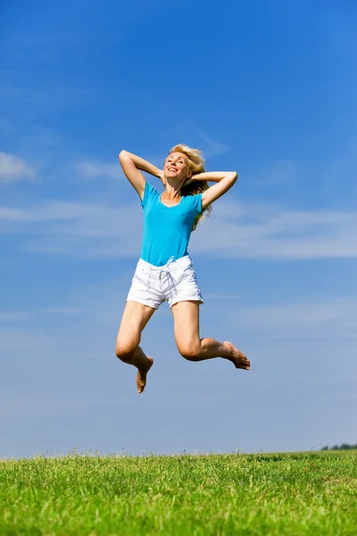 Šťastná mladá žena skočí do pole — Stock fotografie
