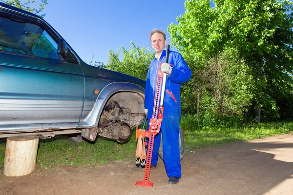 O homem em macacão de trabalho muda uma roda em um carro off-road — Fotografia de Stock