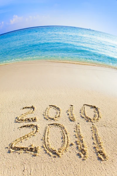 On sand at ocean edge it is written "2010-2011" — Stock Photo, Image